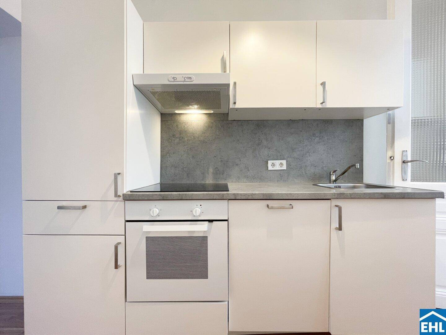 Detailansicht der Küchenzeile mit integriertem Backofen, Kochfeld und Dunstabzugshaube.