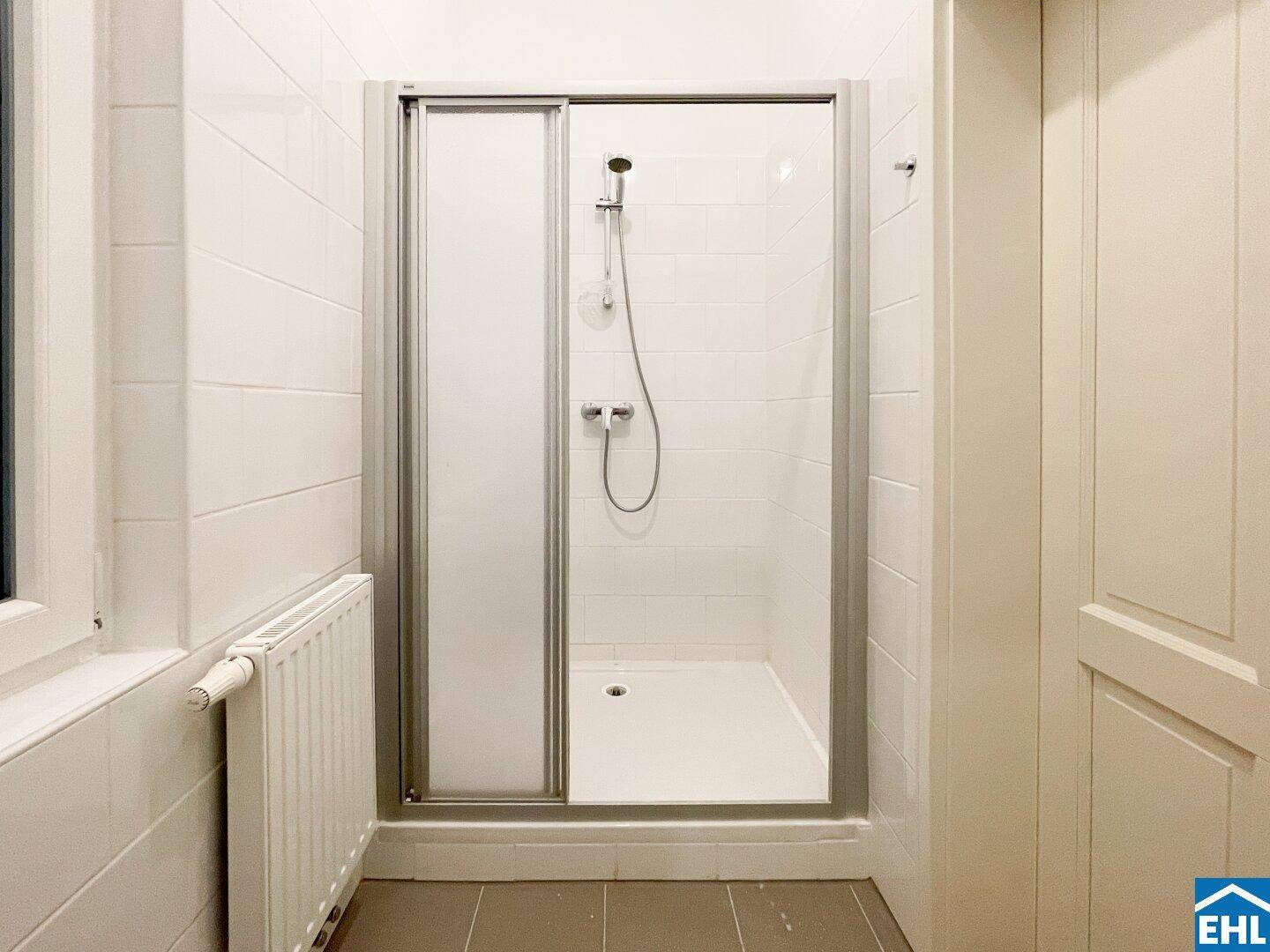 Badezimmer mit moderner Duschkabine und weißen Fliesen, die eine saubere Atmosphäre schaffen.