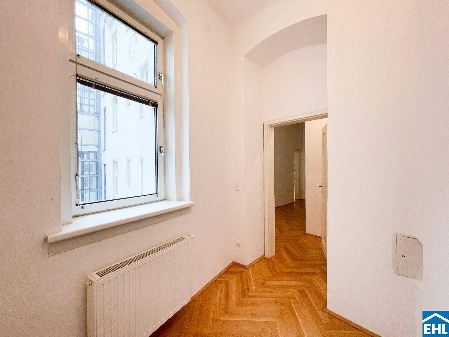 Kleiner Vorraum mit Fenster und Heizkörper, der zu weiteren Räumen führt.