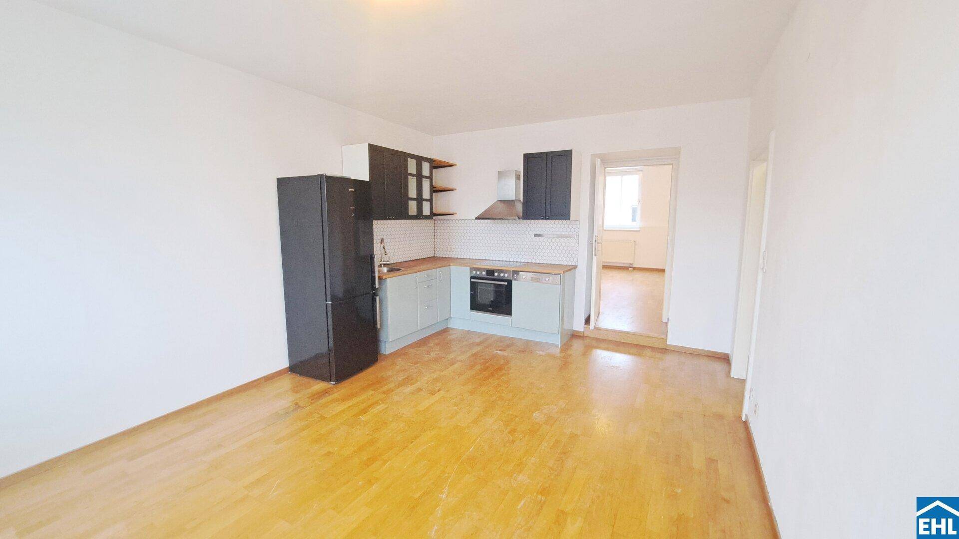 Offener Wohnbereich mit funktionaler Küchenzeile und Zugang zu einem weiteren Zimmer.