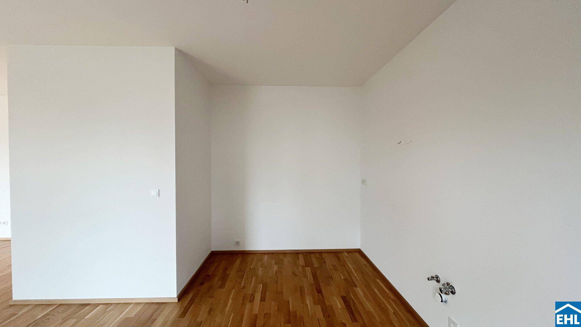 Leerer Raum mit Holzboden und weißen Wänden, bereit für die individuelle Gestaltung.