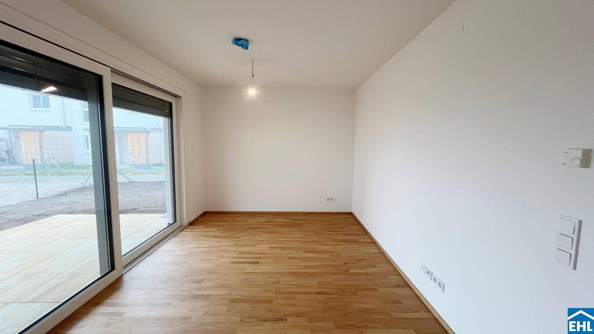 Heller Wohnraum mit großen Schiebetüren zum Außenbereich und attraktivem Holzboden.