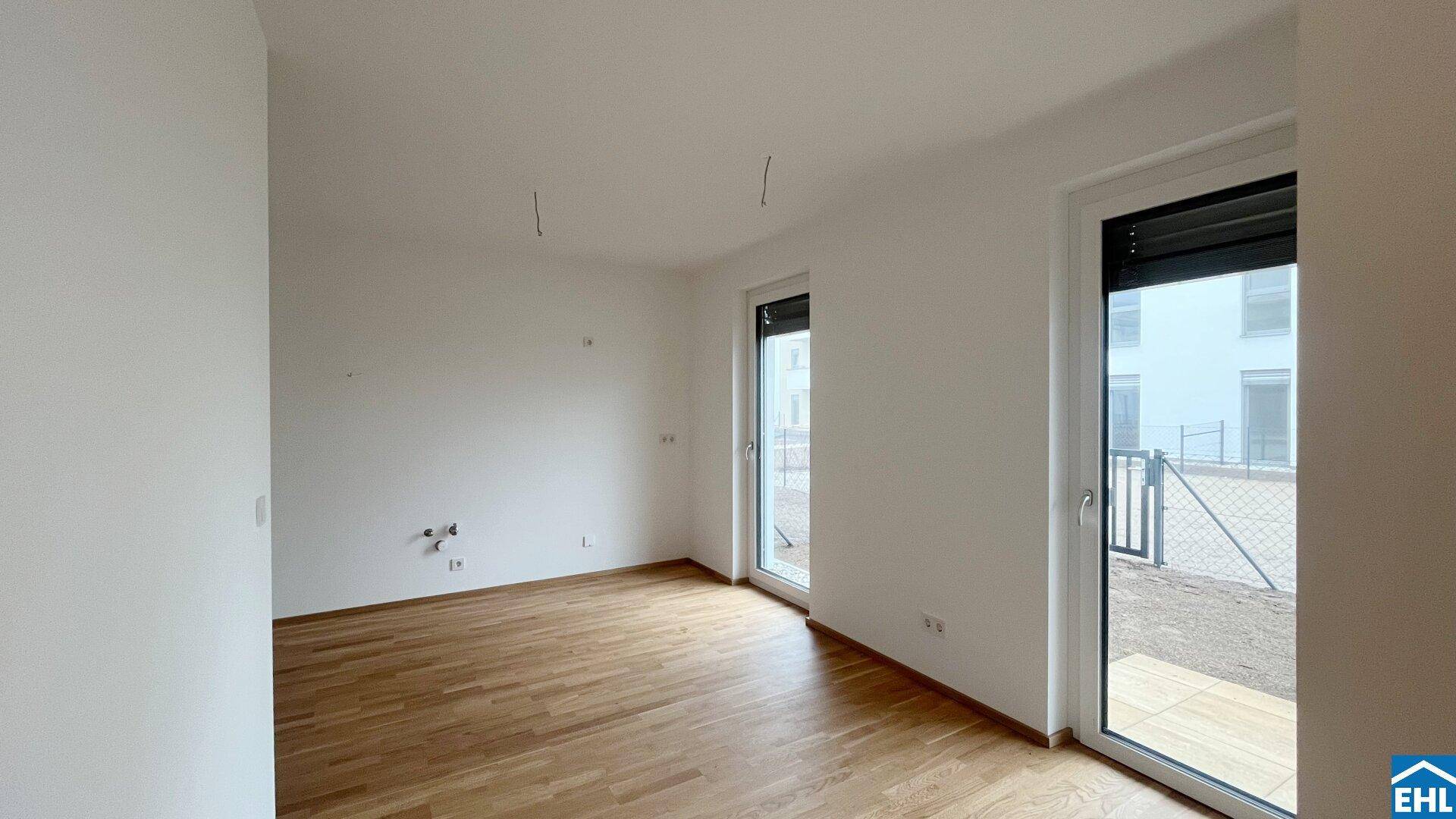 Geräumiges Zimmer mit zwei Zugängen zum Außenbereich und hellem Holzboden.