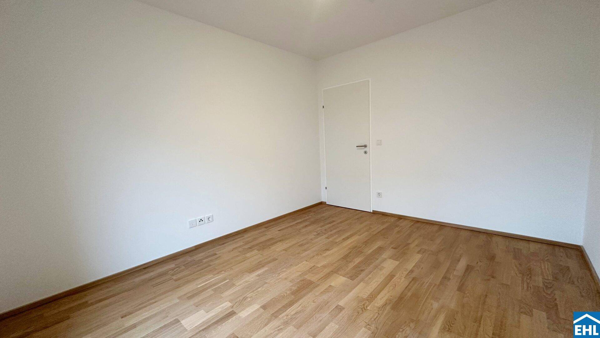 Leeres Zimmer mit Holzparkettboden und weiß gestrichenen Wänden, bietet vielseitige Nutzungsmöglichkeiten.