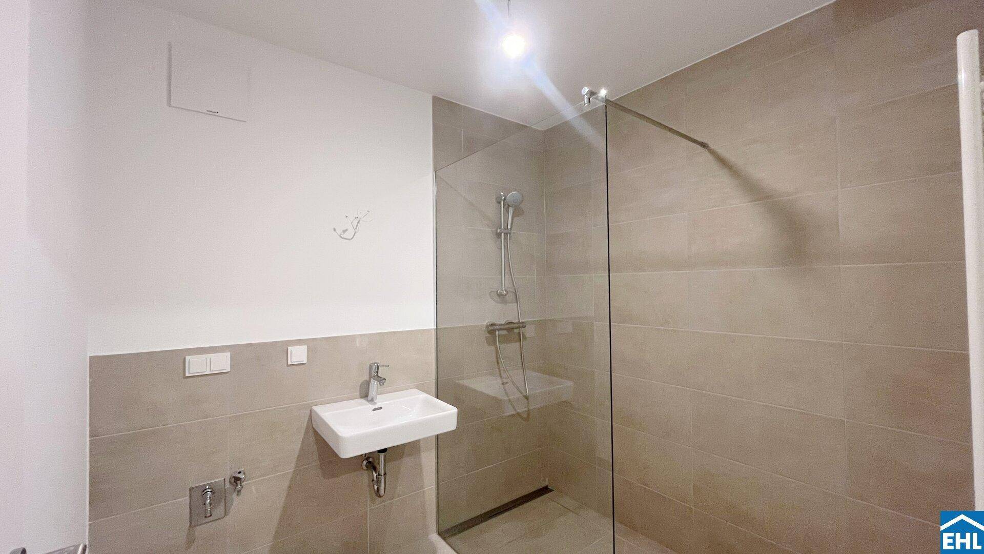Modernes Badezimmer mit begehbarer Dusche, Einzelwaschbecken und beigen Fliesen.