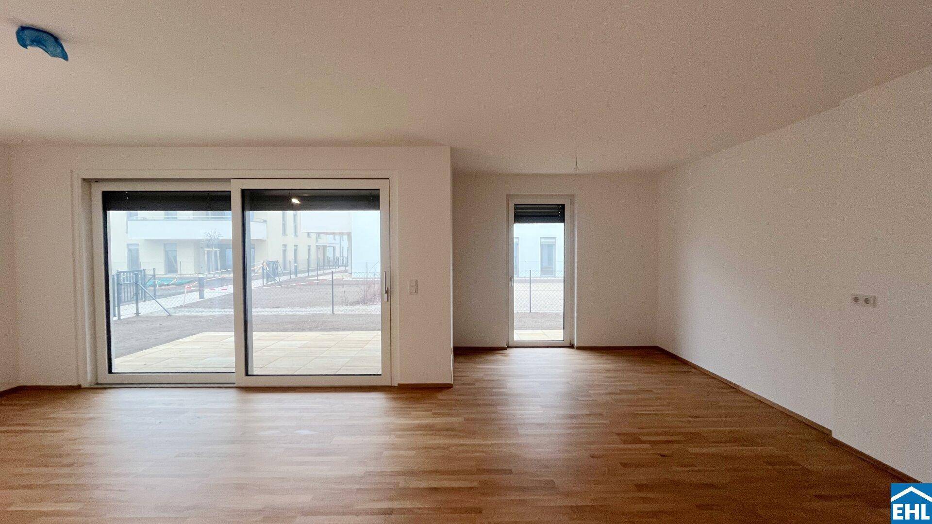 Heller, leerer Raum mit Holzboden und breiten Schiebetüren, die viel Tageslicht hereinlassen.