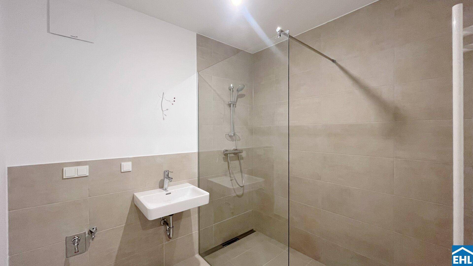 Modernes Badezimmer mit begehbarer Dusche, beigefarbenen Fliesen und einem einzelnen Waschbecken.