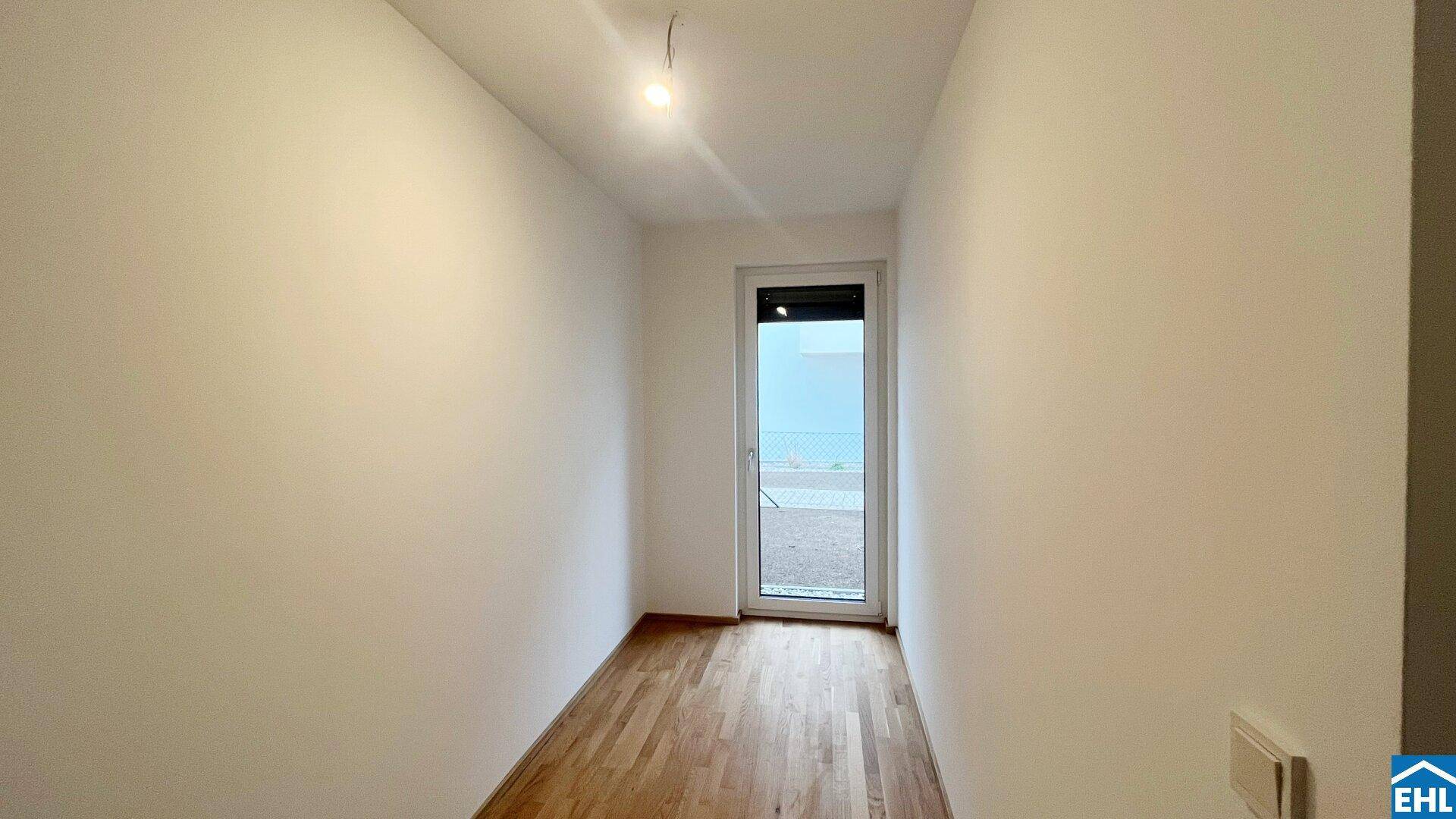Kleines, helles Zimmer mit Holzboden und Zugang zu einem Außenbereich.