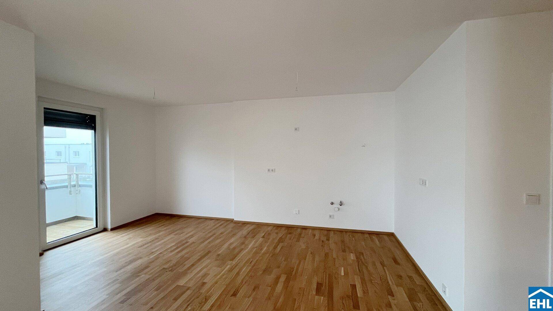 Unmöblierter Raum mit Anschlüssen für eine Küche und Zugang zu einem französischen Balkon.