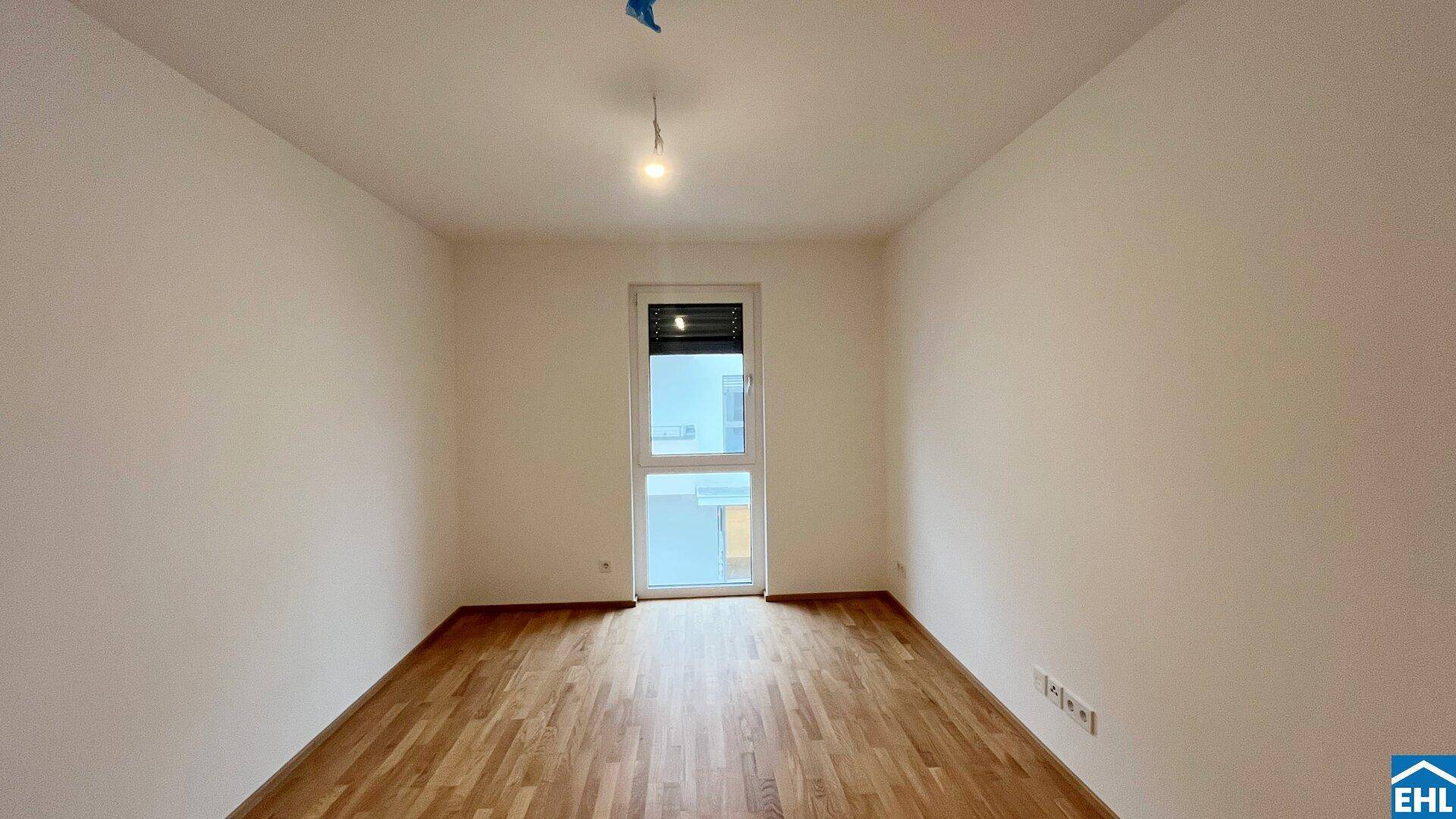 Helles, unmöbliertes Zimmer mit Parkettboden und großem Fenster für natürliche Belichtung.