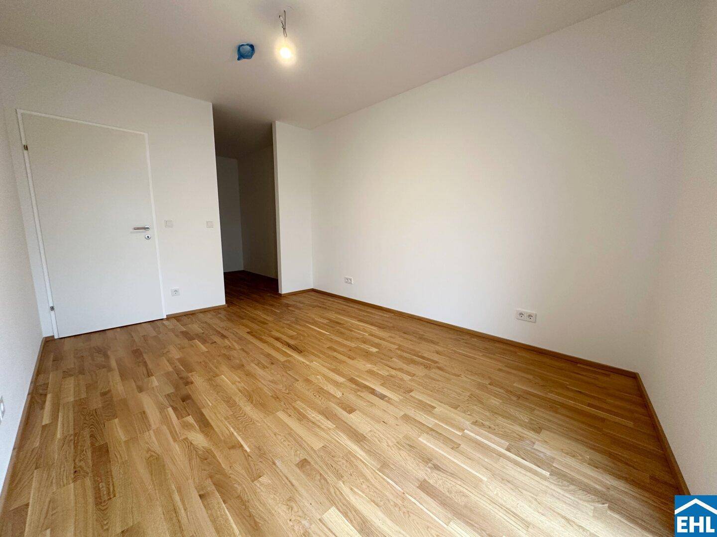 Geräumiges, unmöbliertes Zimmer mit Parkettboden und weiß gestrichenen Wänden, ideal für Schlaf- oder Arbeitsbereich.