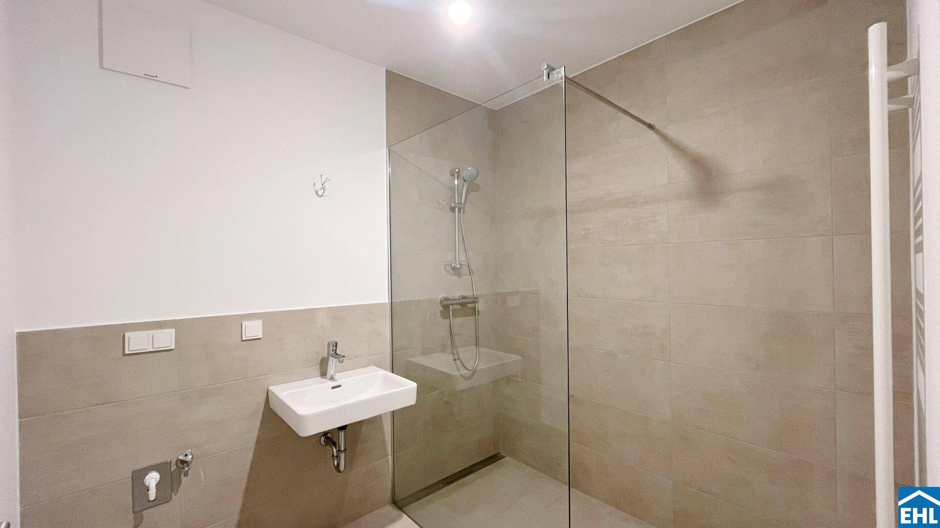 Modernes Badezimmer mit begehbarer Dusche, Wand-WC und beheiztem Handtuchhalter.