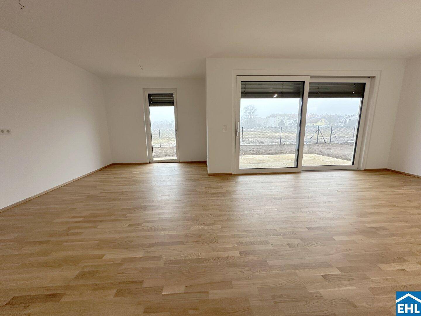 Geräumiger, heller Raum mit Parkettboden und großen Schiebetüren zum Außenbereich.