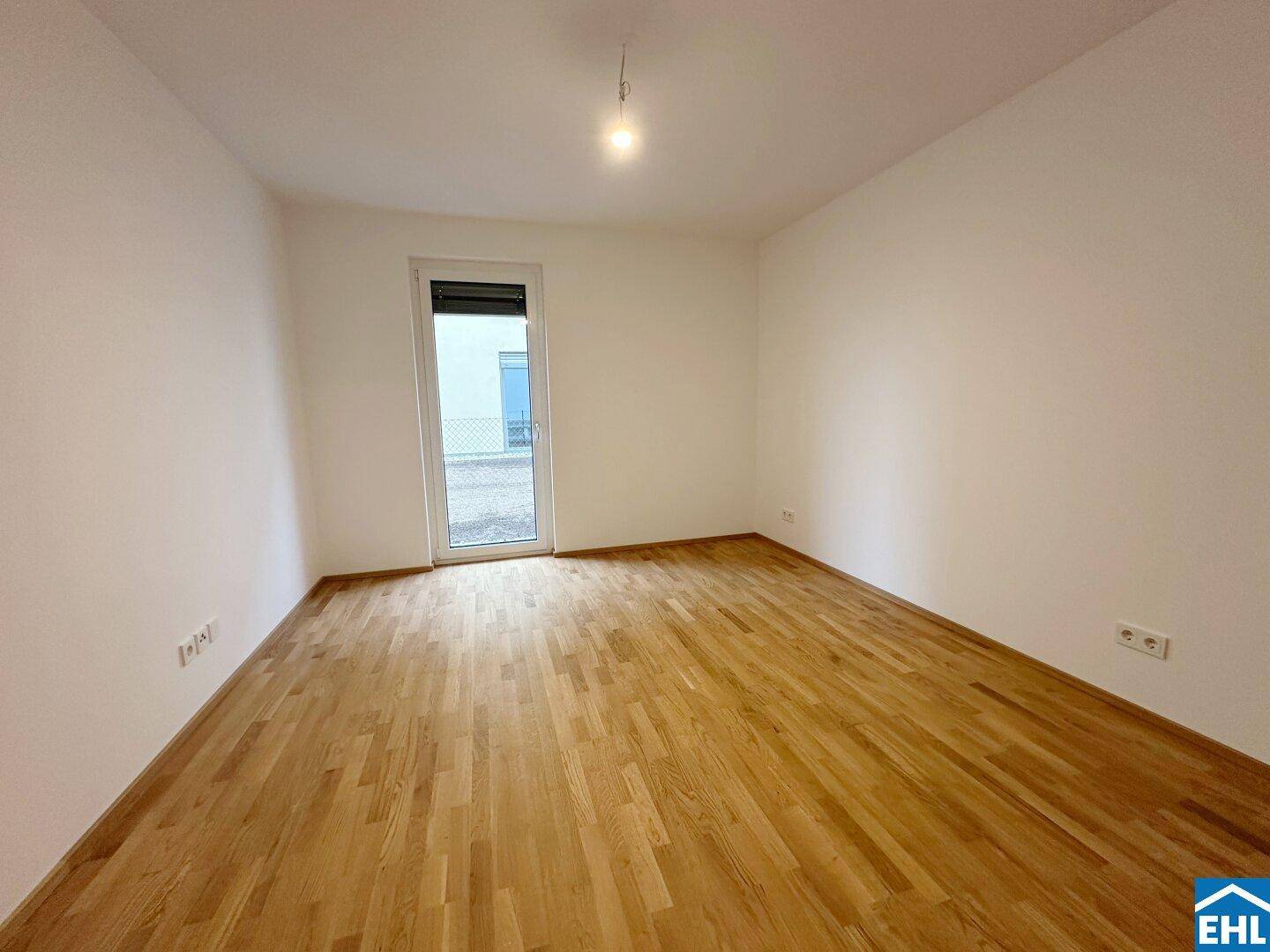 Helles Schlafzimmer mit Parkettboden und Fenster mit Rollladen.