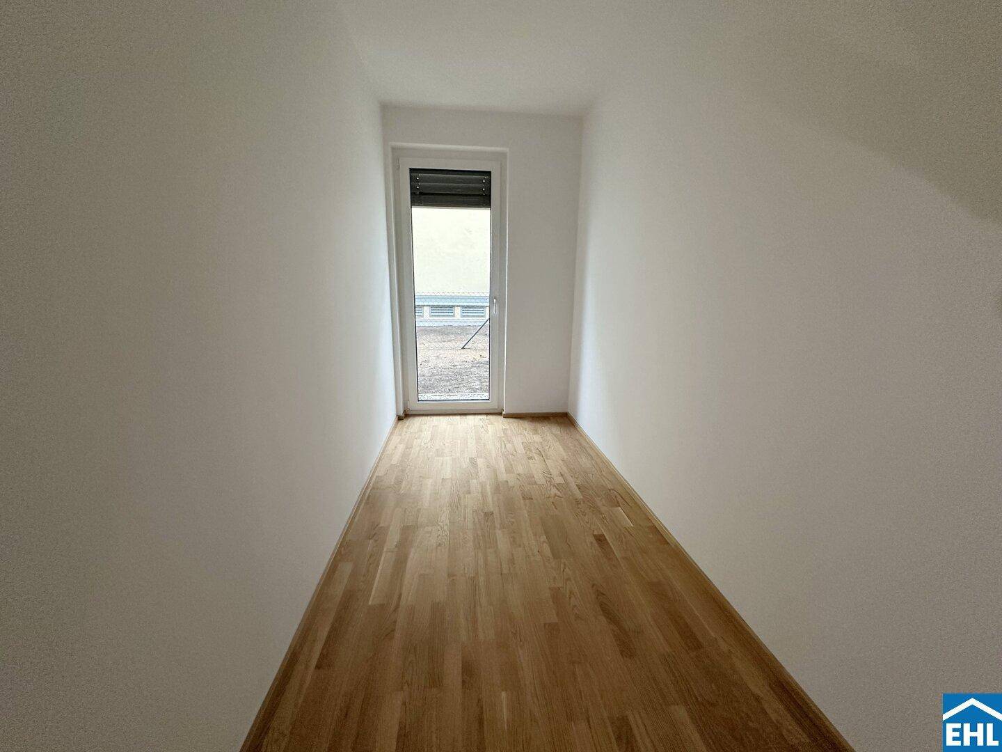Schmaler Raum mit Parkettboden und Fenster, ideal als Kinder- oder Arbeitszimmer.