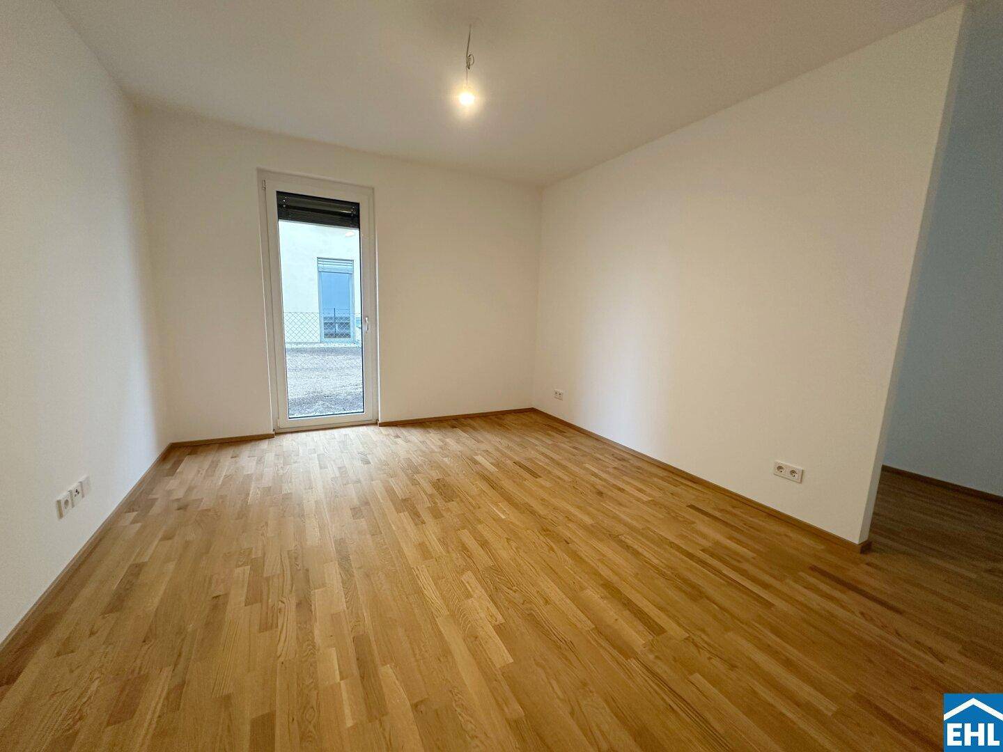 Helles Zimmer mit Parkettboden und Fenster, das viel Tageslicht bietet.