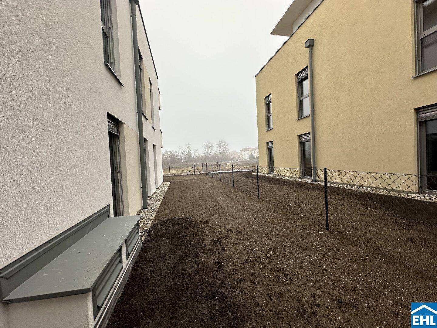 Außenbereich zwischen zwei modernen Gebäuden mit vorbereitetem Gartenland.