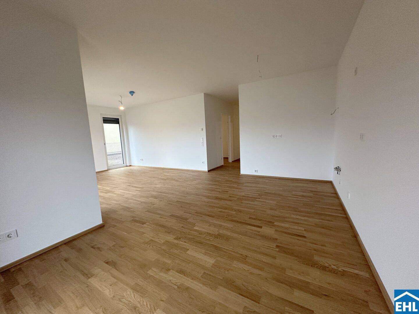 Großer, heller Wohnbereich mit Parkettboden und mehreren Zugängen zu anderen Räumen.