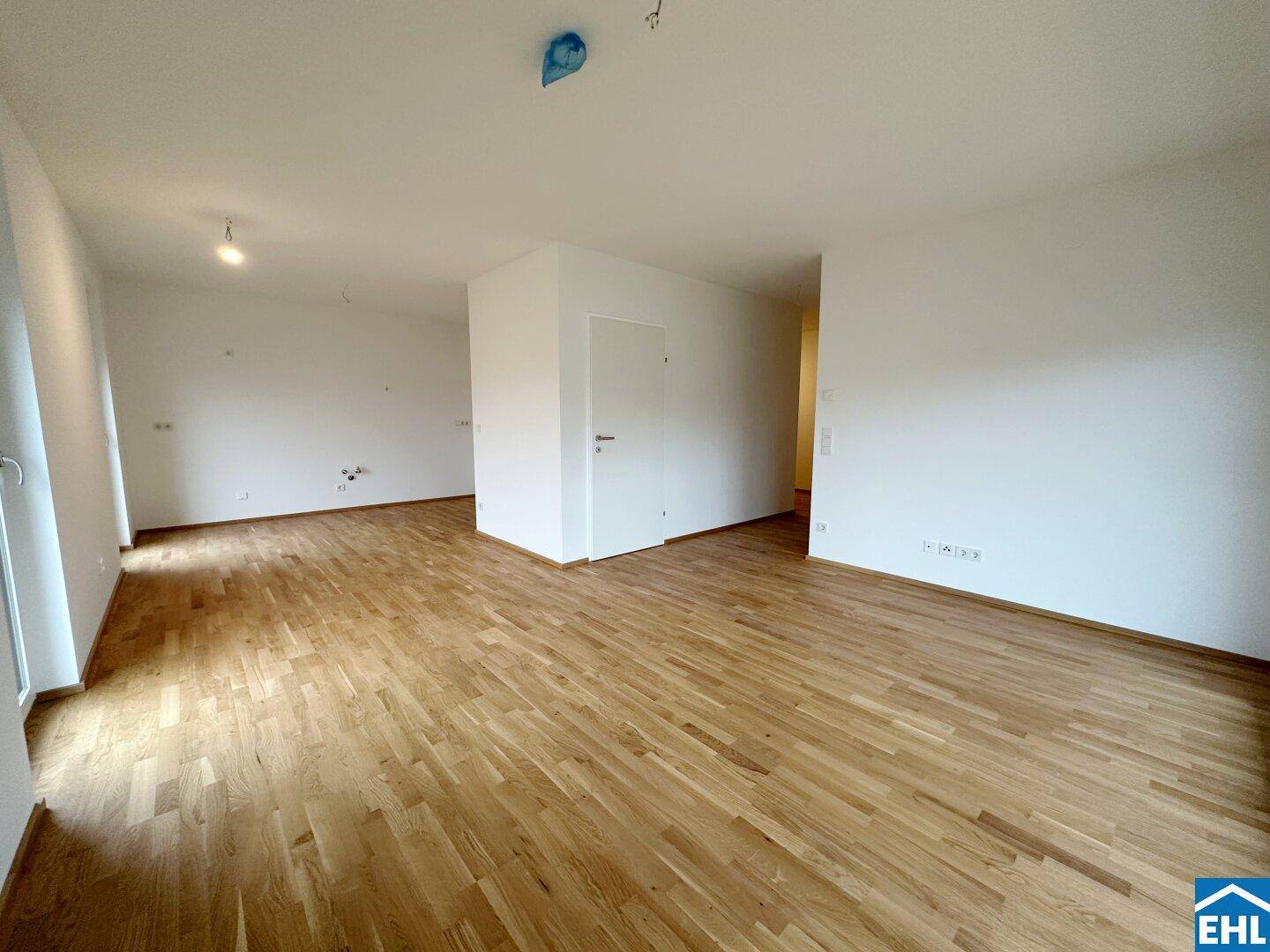 Offener Wohnbereich mit hellem Holzboden und weißen Wänden, bereit zur individuellen Gestaltung.