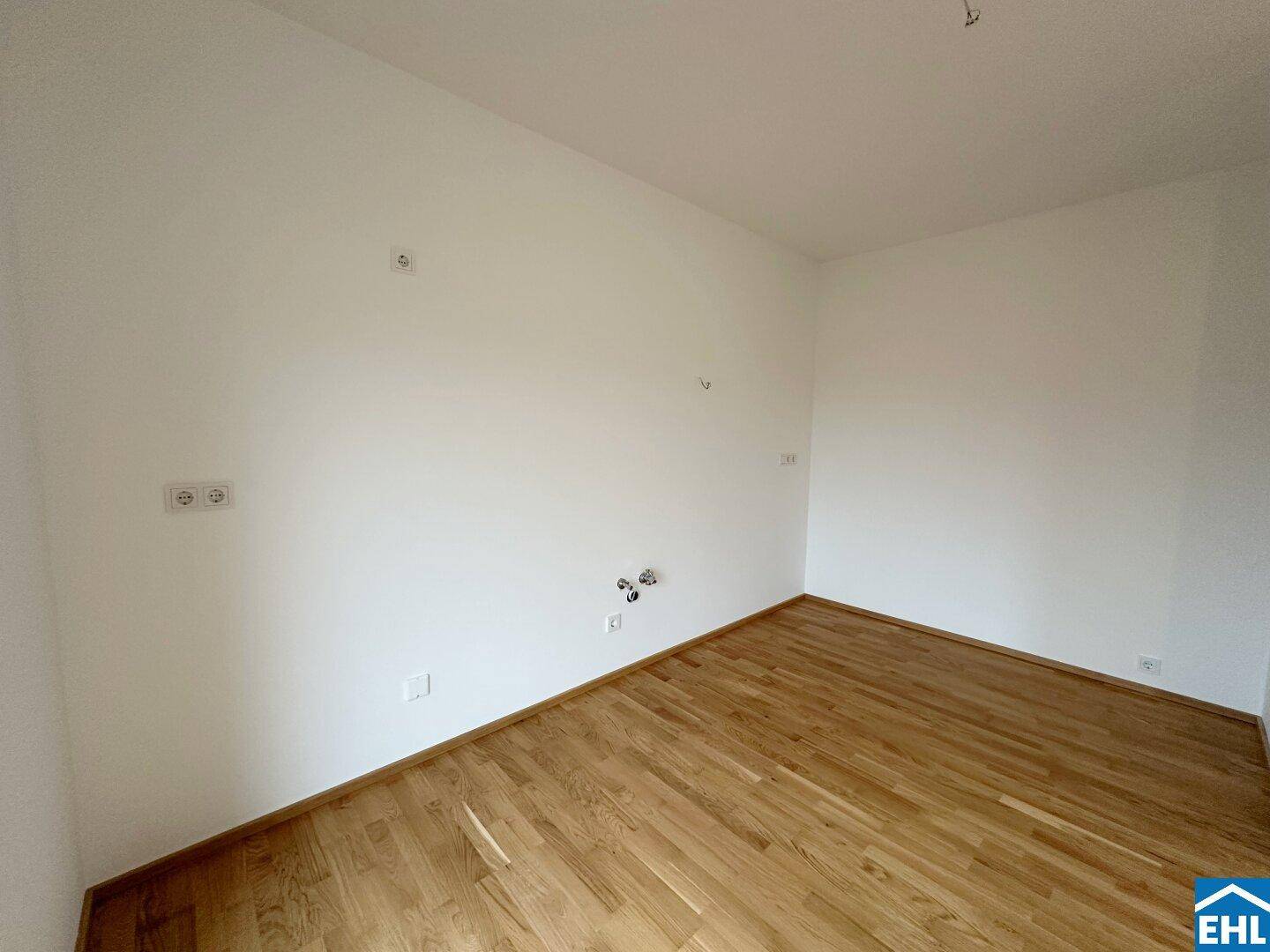 Leerer Raum mit Holzboden und weißen Wänden, ideal für ein Schlafzimmer oder Büro.