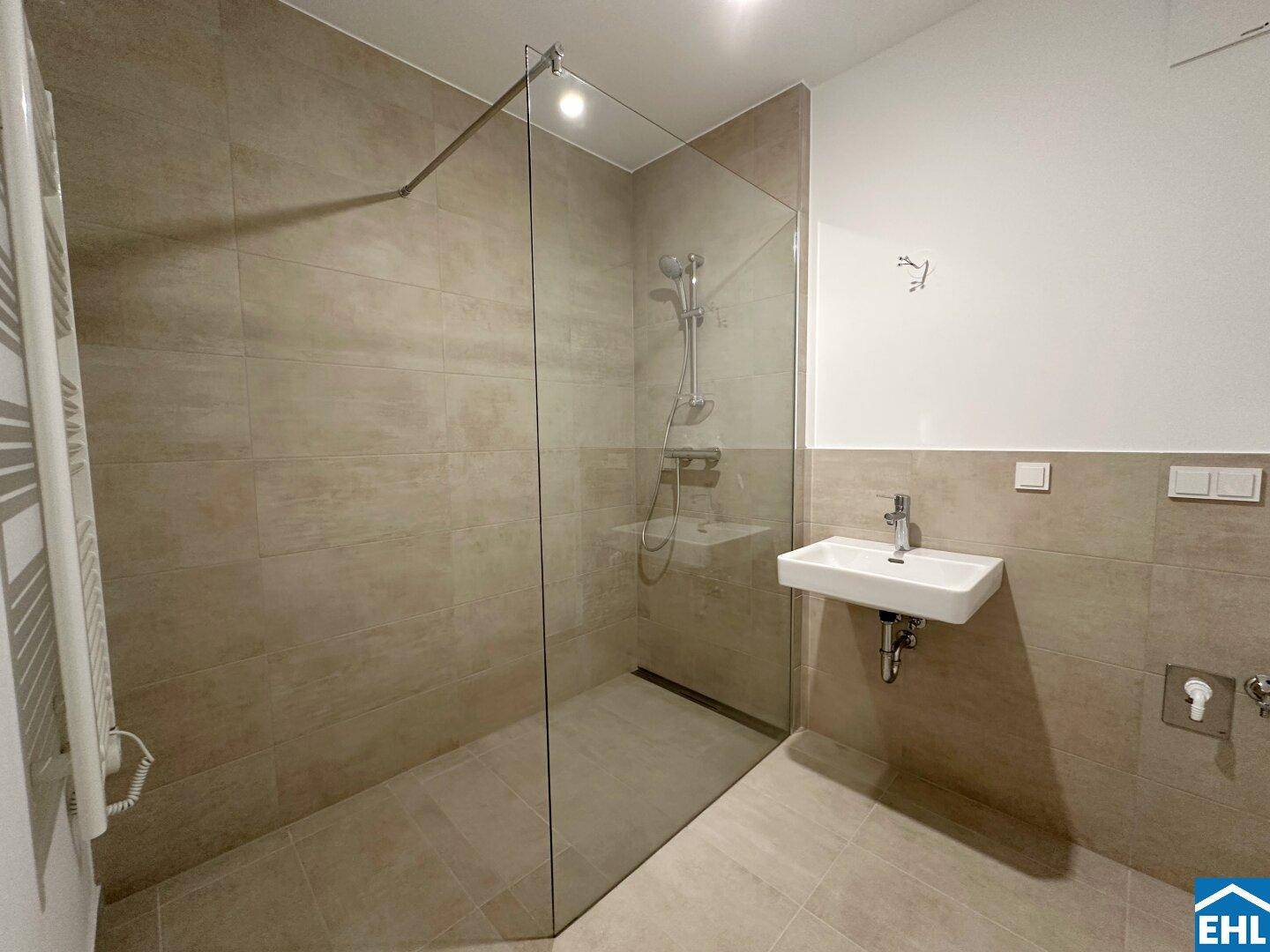 Modernes Badezimmer mit begehbarer Dusche, beigefarbenen Fliesen und einem einzelnen Waschbecken.