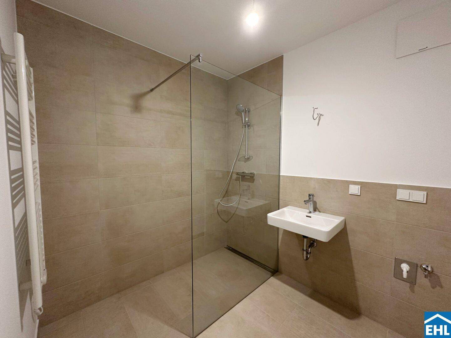 Zeitgemäßes Badezimmer mit großer begehbarer Dusche, Wandfliesen und einem Handtuchheizkörper.