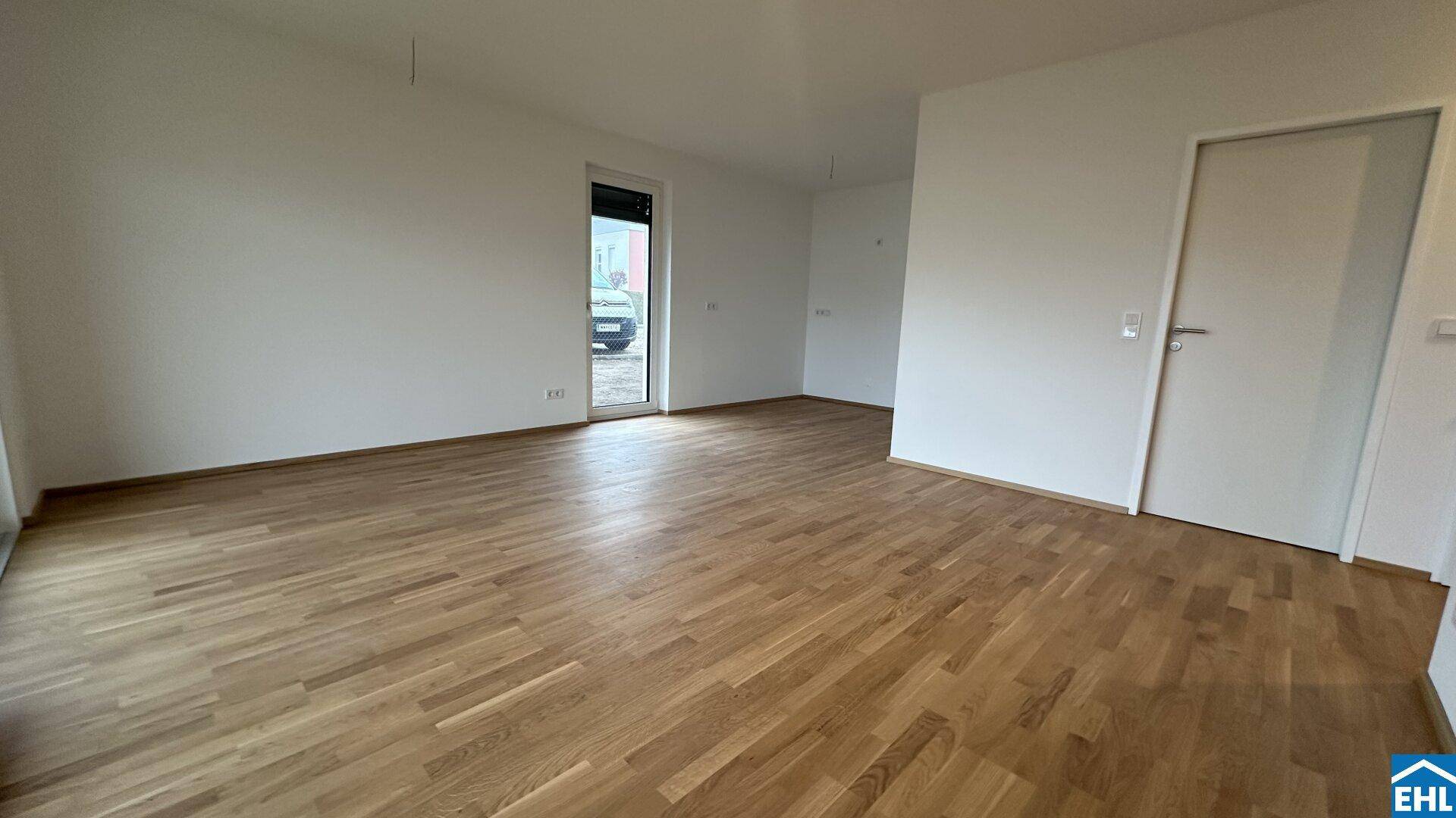 Leeres Zimmer mit Holzboden und einer Tür, die nach draußen führt, ideal für individuelle Gestaltung.