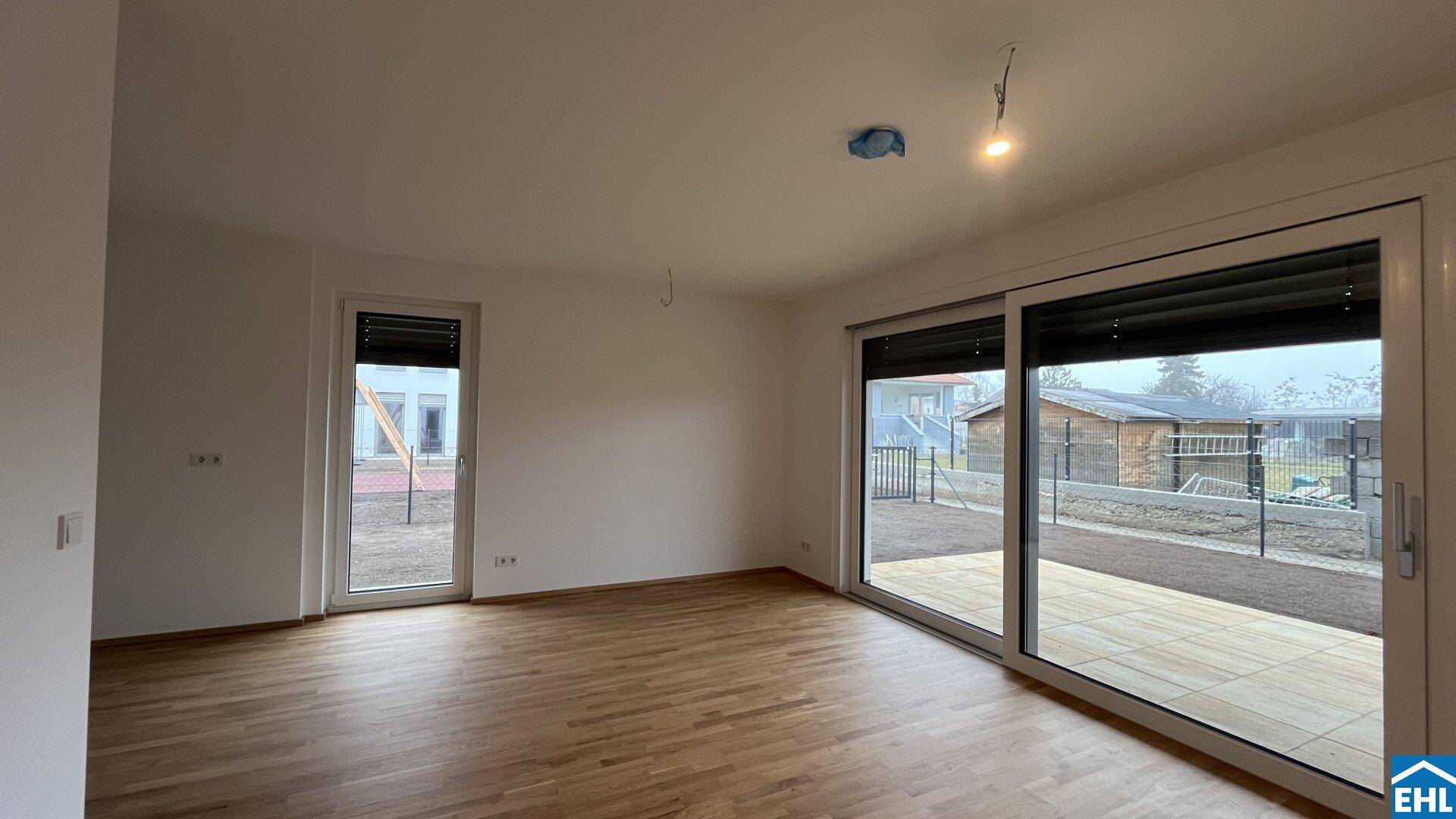 Geräumiges Wohnzimmer mit zwei großen Fenstern und Zugang zum Gartenbereich.