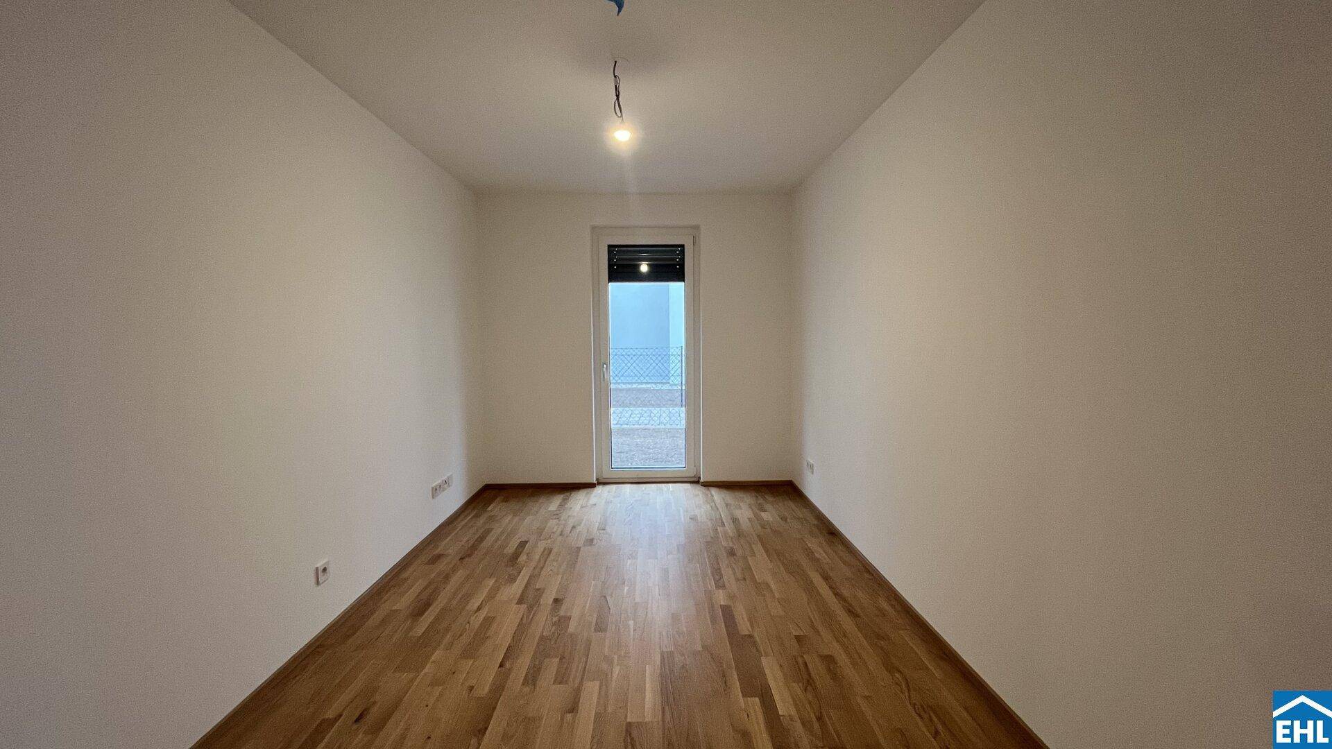 Leeres Zimmer mit Parkettboden und Fenstertür, ideal als Schlaf- oder Arbeitszimmer.