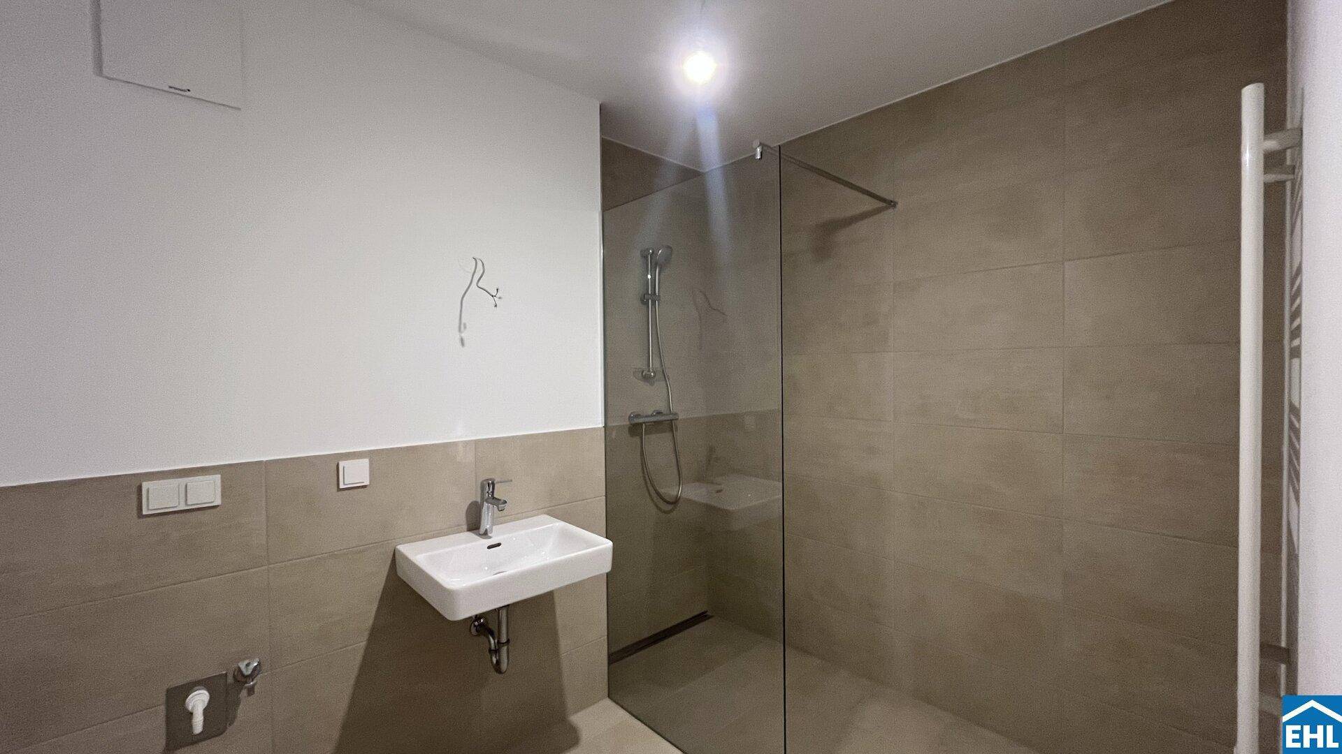 Modernes Badezimmer mit begehbarer Dusche, Einzelwaschbecken und beheiztem Handtuchhalter.