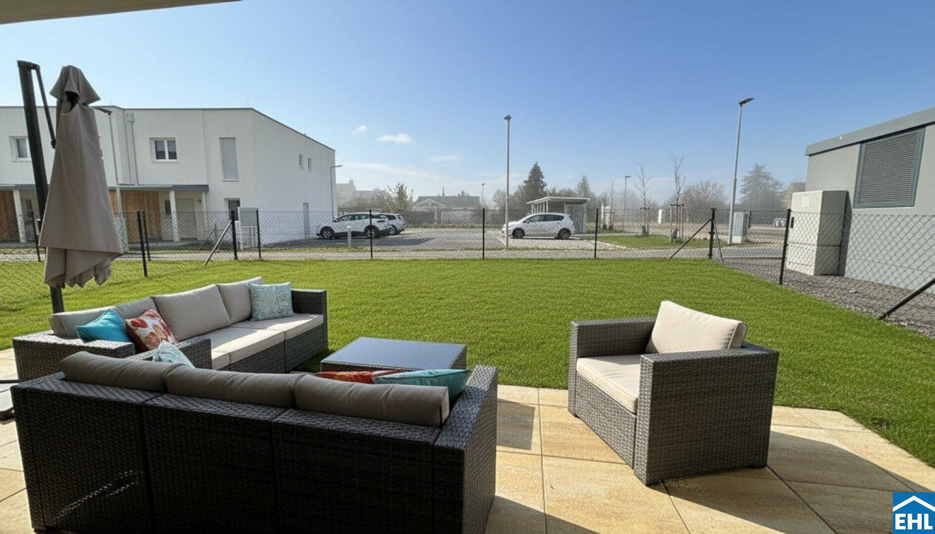 Gemütliche Terrasse mit Outdoor-Sitzmöbeln und Blick auf den Rasen und die umliegenden Häuser.