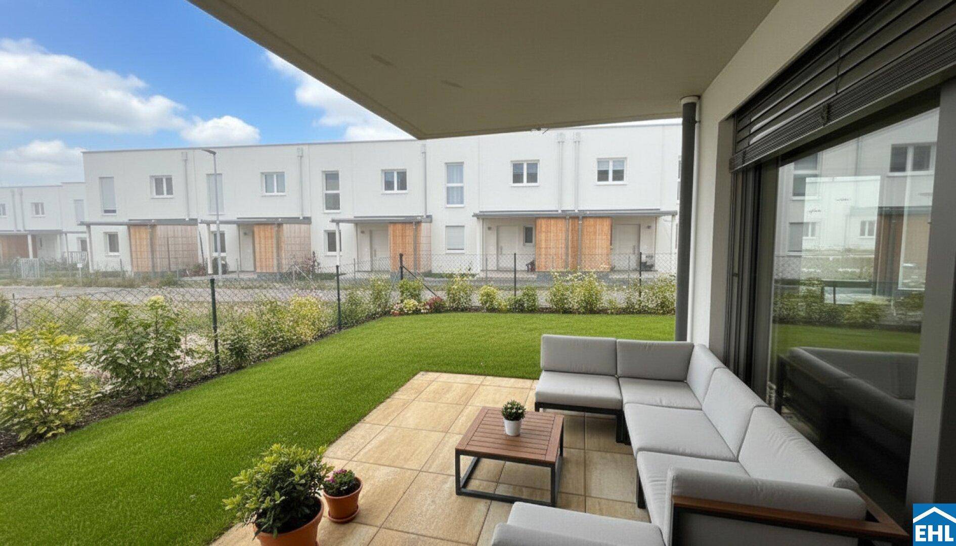 Moderne Terrasse mit Gartenmöbeln und angrenzendem Rasenbereich vor Reihenhäusern.