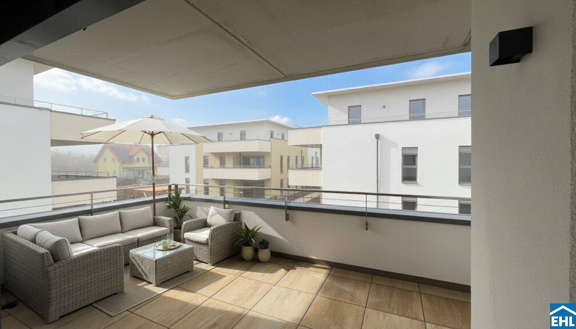 Geräumiger Balkon mit Outdoor-Sitzbereich und Blick auf die umliegenden Neubauten.