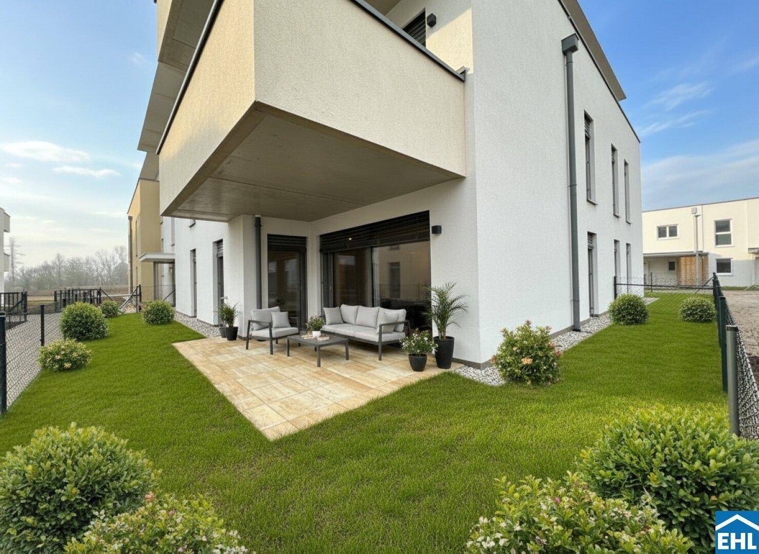 Sonniger Außenbereich mit möblierter Terrasse und angrenzendem Rasen, ideal zum Entspannen.