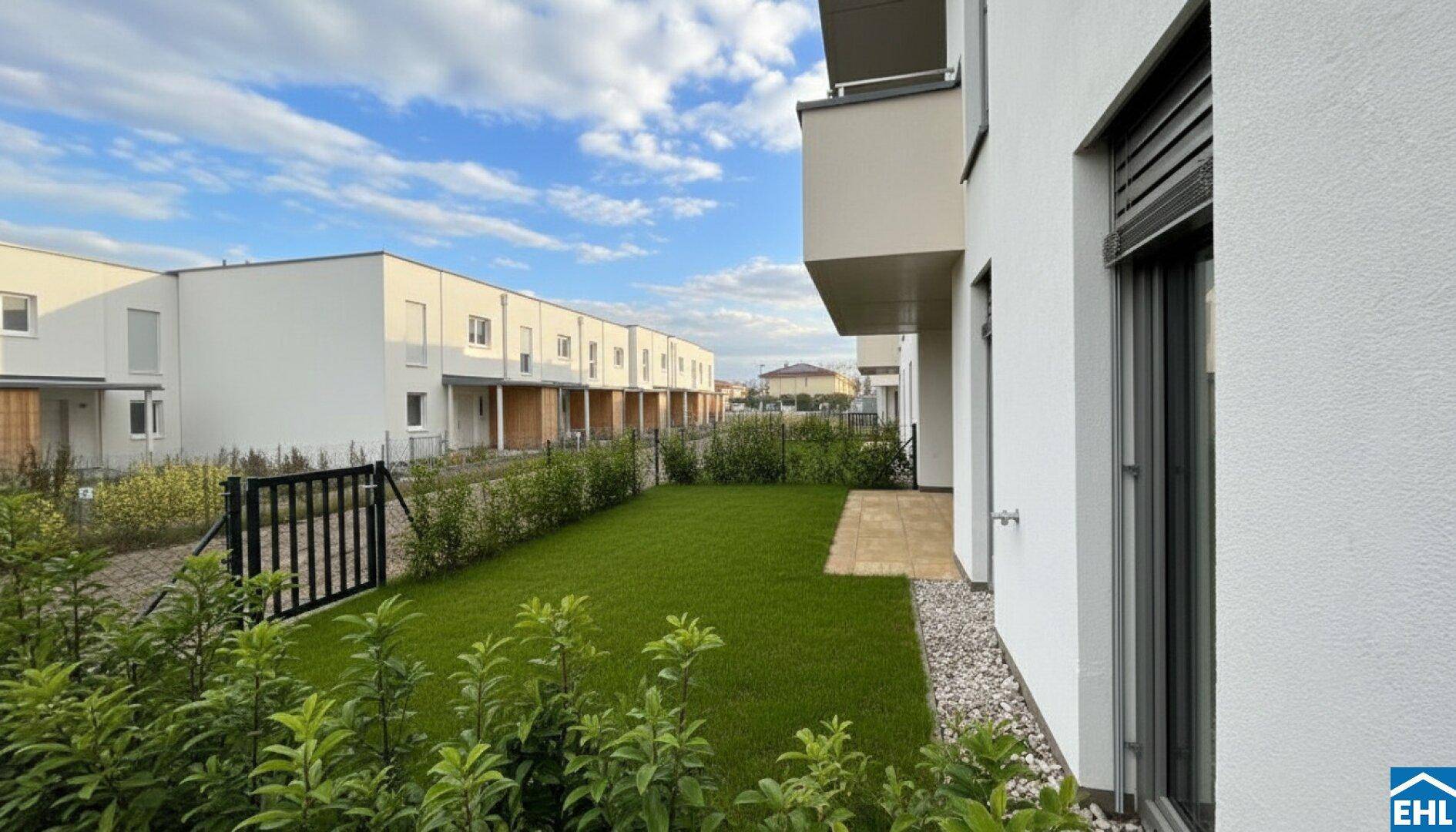Gepflegter Gartenbereich mit Rasenfläche und Blick auf die modernen Reihenhäuser.