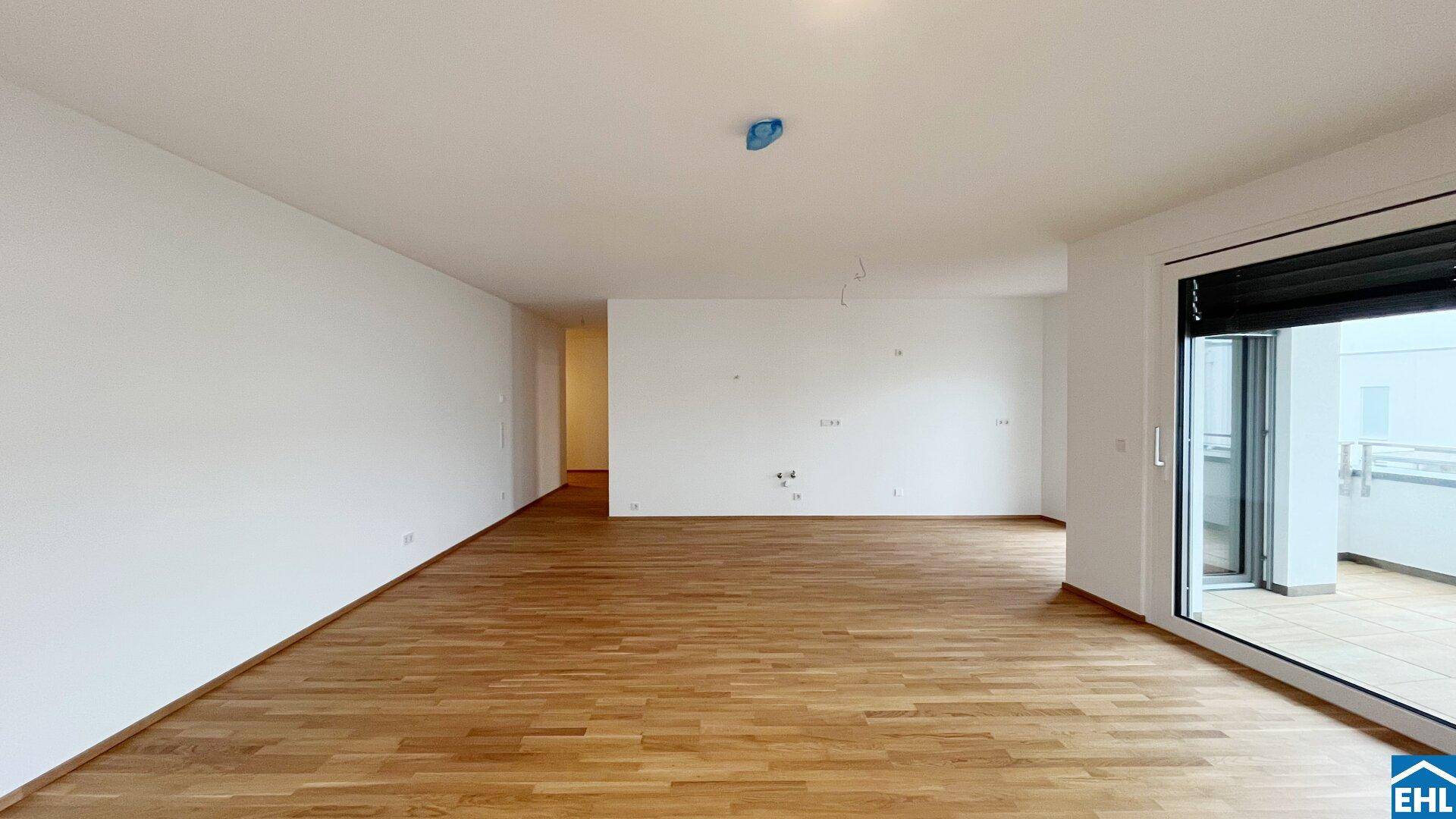 Leerer Wohnbereich mit Holzboden und Schiebetür zum Außenbereich, bereit zur individuellen Gestaltung.
