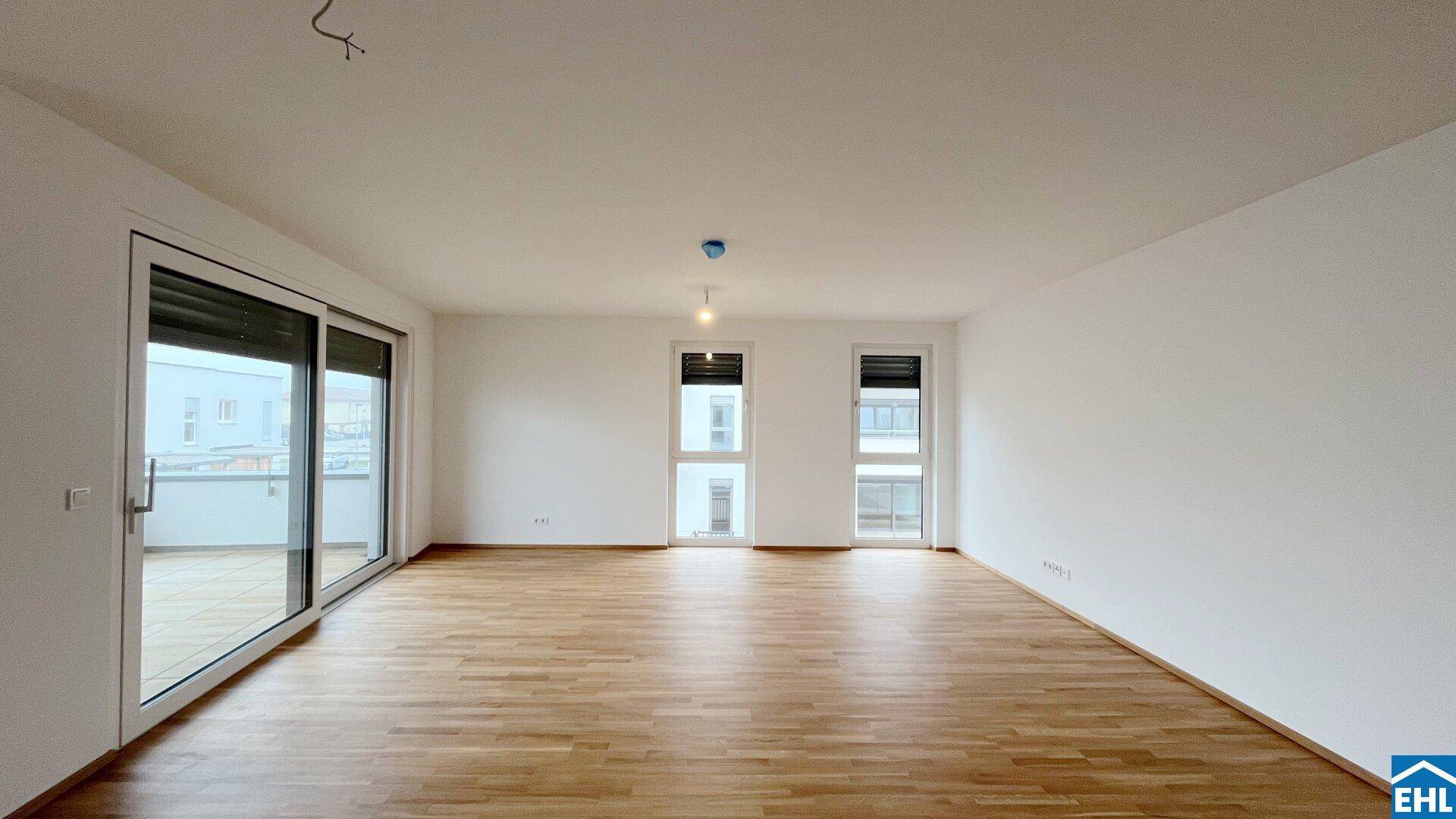 Unmöblierter Raum mit Parkettboden und großen Fenstern, die viel Tageslicht hereinlassen.