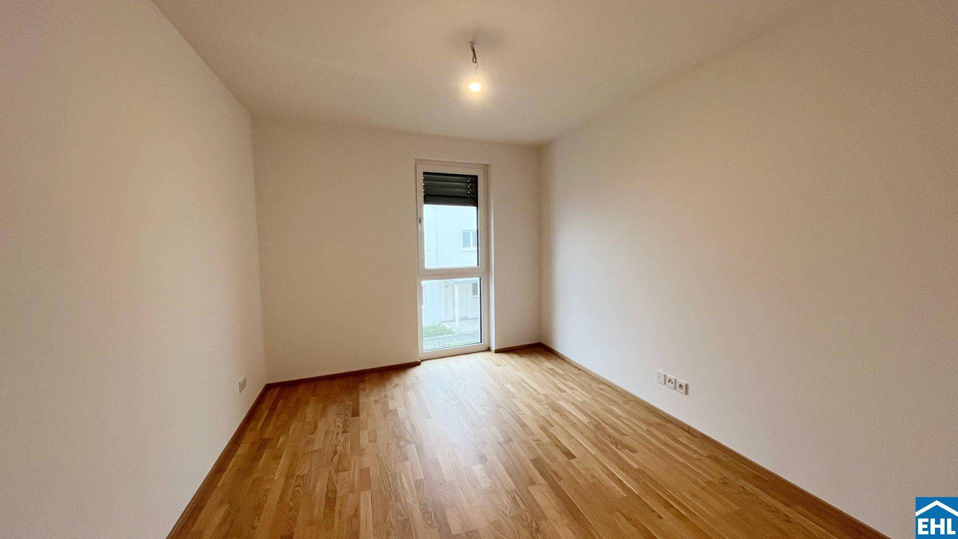 Helles, unmöbliertes Zimmer mit Parkettboden und Zugang zu einem französischen Balkon.