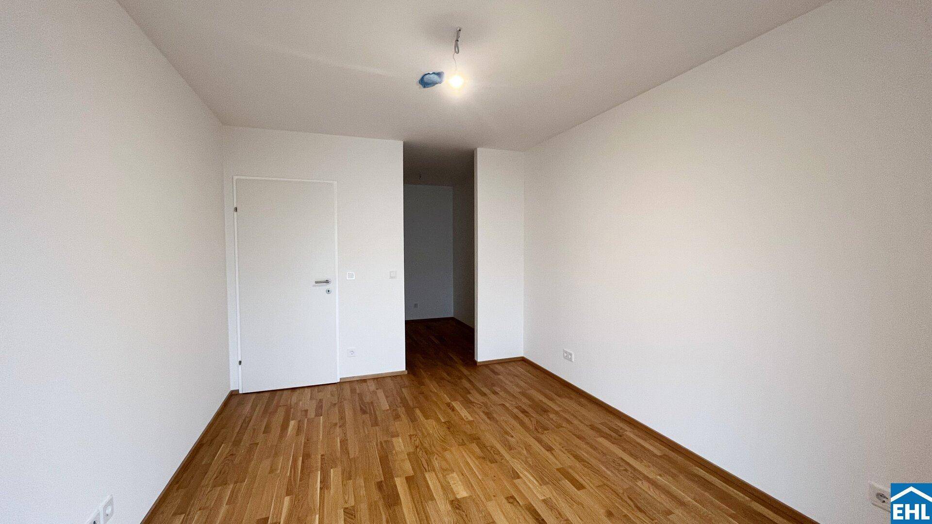 Leeres Zimmer mit Holzboden und weiß gestrichenen Wänden, bereit zur Einrichtung.