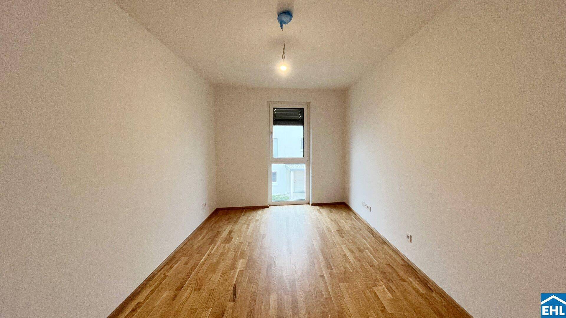 Unmöbliertes Zimmer mit Parkettboden und Fenster, das viel Tageslicht bietet.