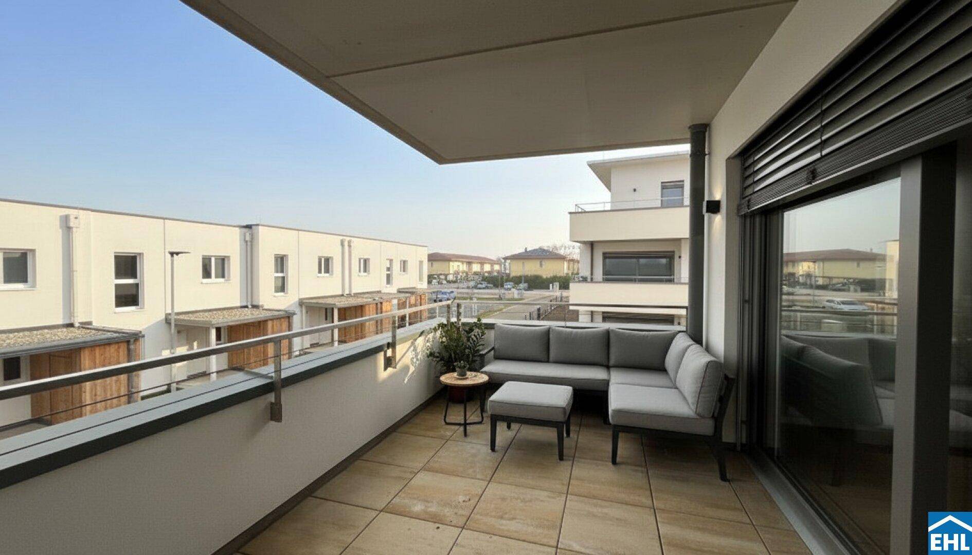 Möblierter Balkon mit bequemen Sitzgelegenheiten und Blick auf die umliegenden Gebäude.