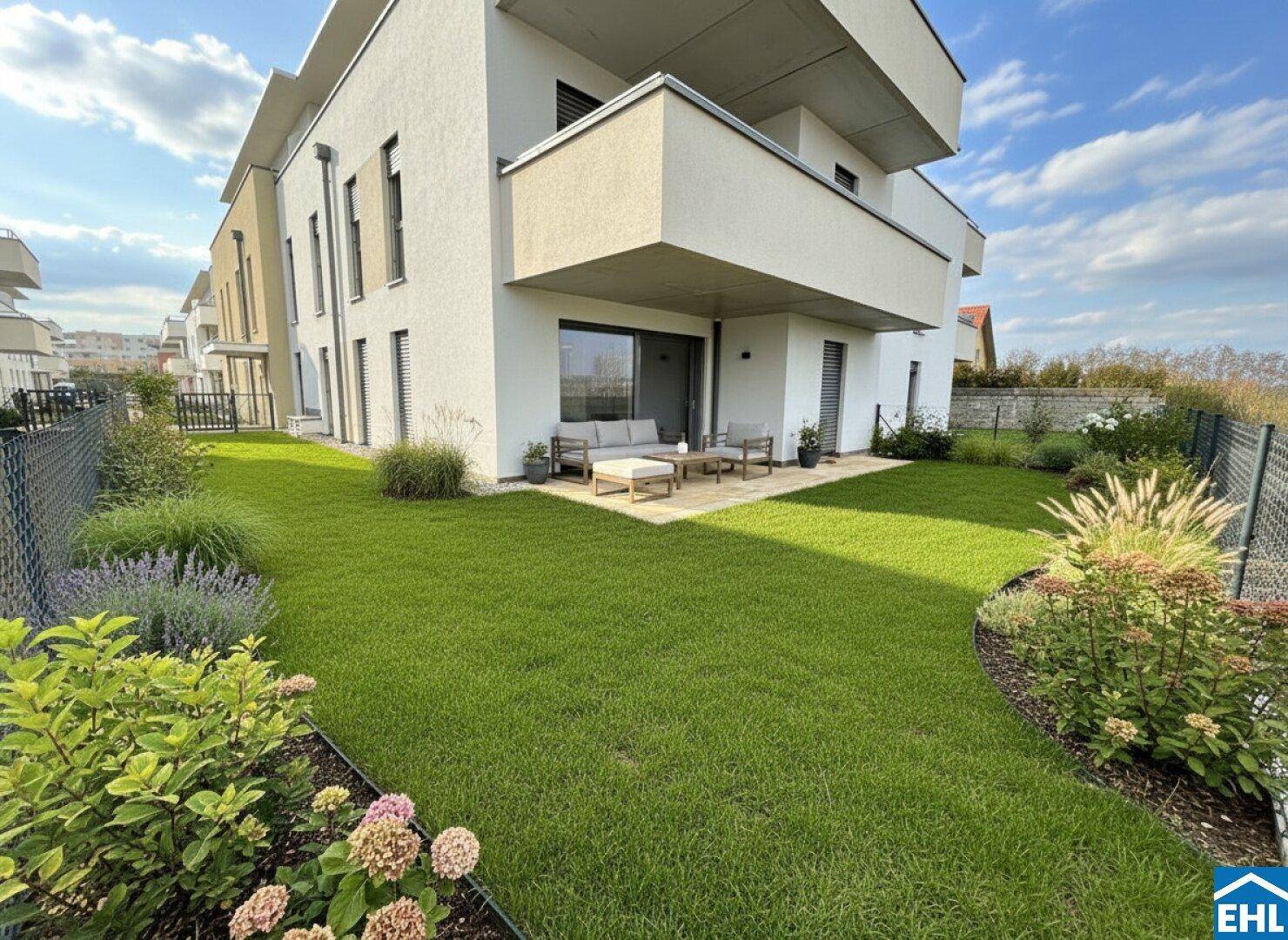 Moderne Wohnanlage mit gepflegtem Gartenbereich und möblierter Terrasse im Erdgeschoss.