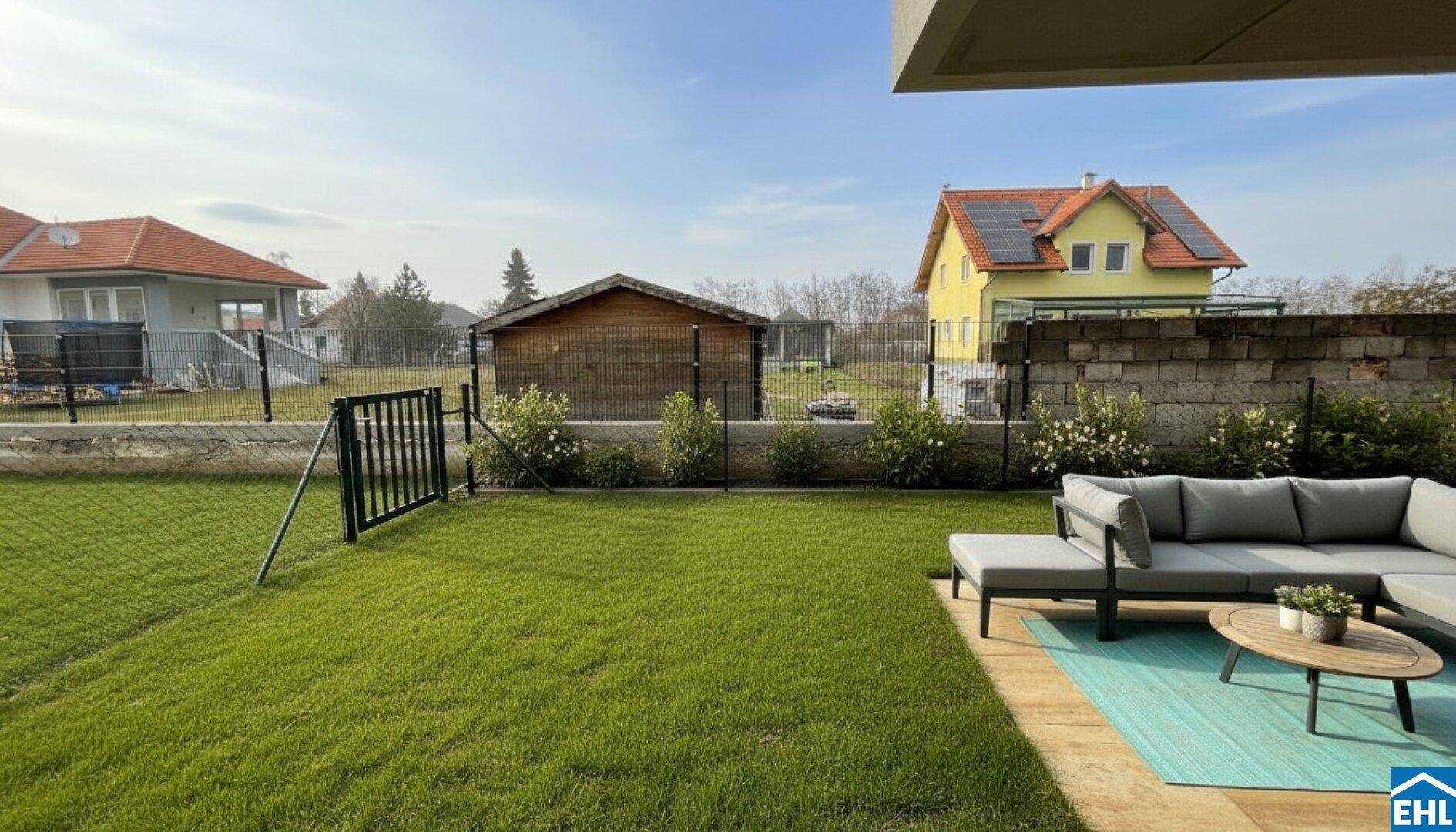 Gepflegter Garten mit Rasenfläche, Sitzbereich und Blick auf die Nachbarschaft.