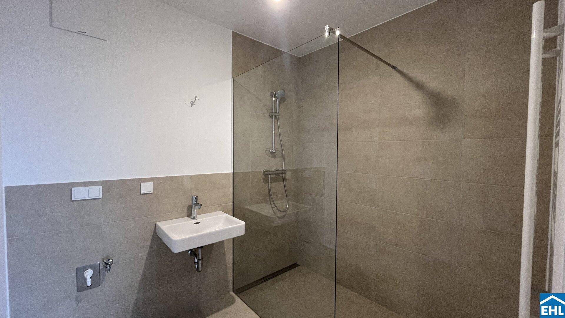 Modernes Badezimmer mit begehbarer Dusche, Wand-WC und beheiztem Handtuchhalter.