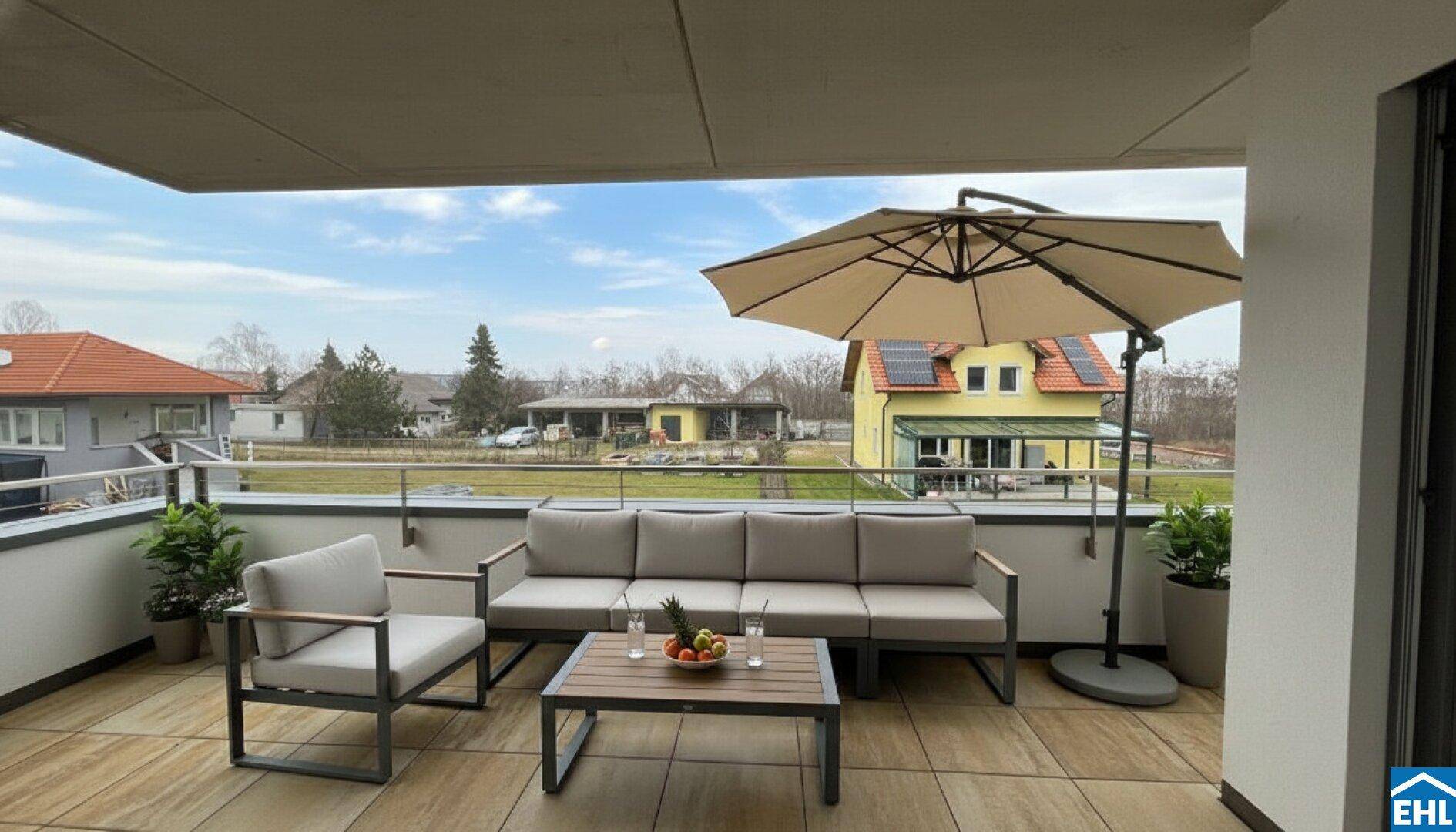 Geräumige Terrasse mit modernen Gartenmöbeln, Sonnenschirm und weitem Blick ins Grüne.