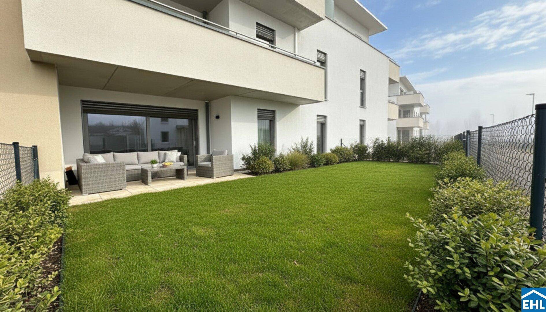 Große Terrasse mit modernen Gartenmöbeln und angrenzendem Rasenbereich vor einem Neubau.