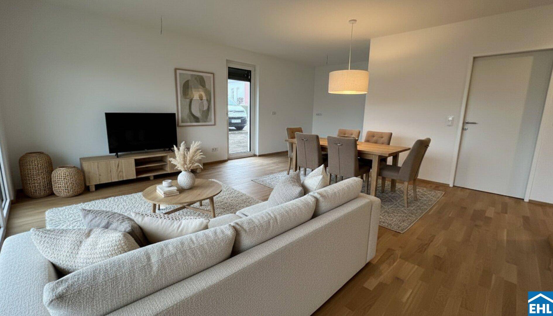 Offener Wohn-Essbereich mit hellem Sofa, Esstisch und Holzboden, modern eingerichtet.