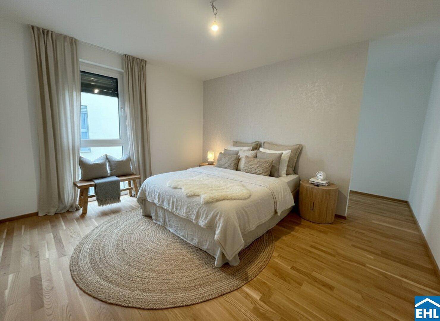 Gemütliches Schlafzimmer mit Holzboden, runder Teppich und großem Fenster für viel Licht.