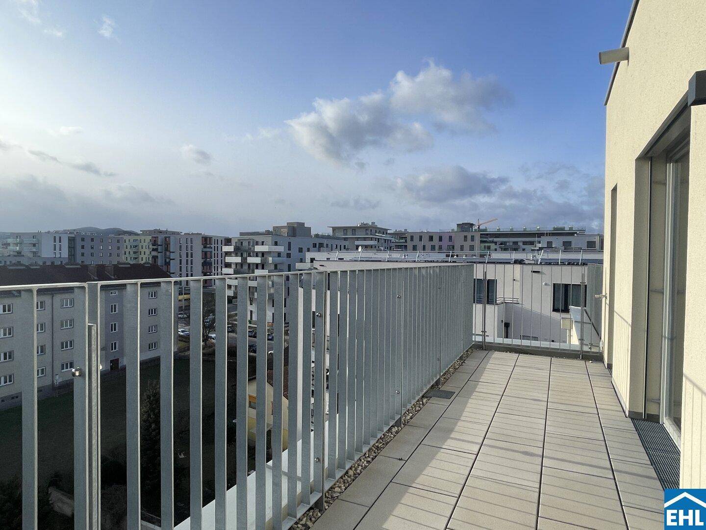 Weitläufige Dachterrasse mit Blick auf die umliegende Stadtbebauung und den Himmel.