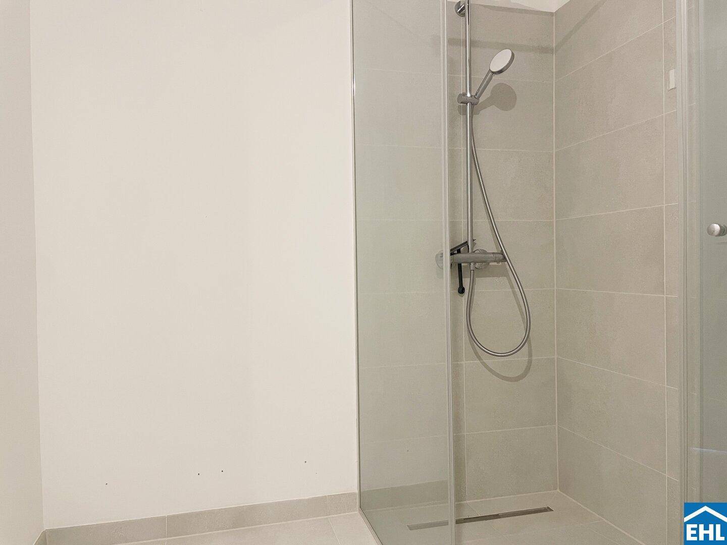 Moderne Duschkabine mit Glasabtrennung und hellen Fliesen im Badezimmer.